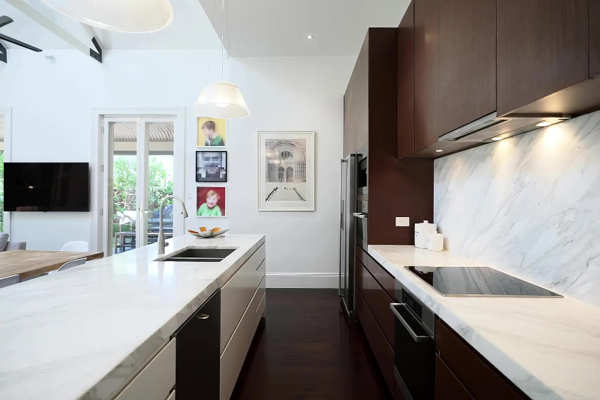 A kitchen with sleek marble counter tops and a pristine white wall.